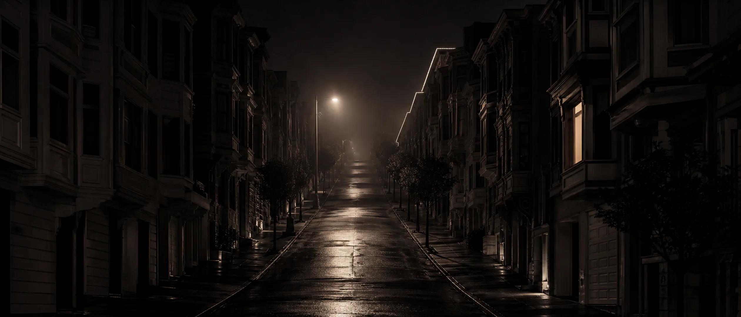 A foggy San Francisco street lined with Victorian rowhouses, lit by a single streetlamp at night.